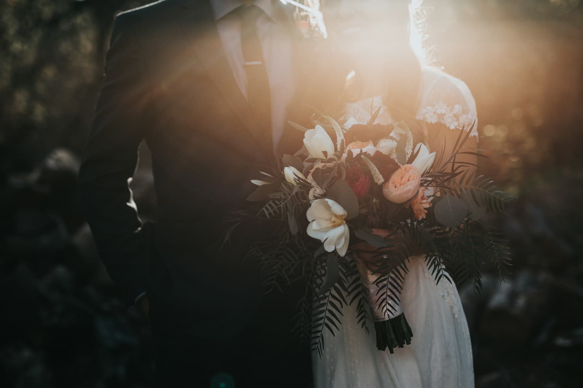 Beach wedding setup with white chairs and floral arch at sunset